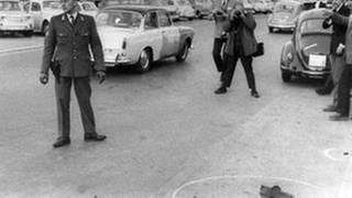 Ein Fotograf macht Aufnahmen von Rudi Dutschkes Schuhen, die, von der Polizei markiert, noch am Tatort liegen