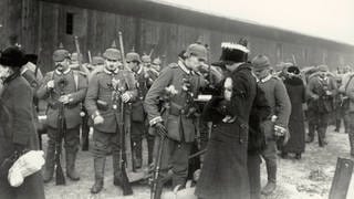 Ein Soldat nimmt Abschied von seiner Frau oder Freundin, im Hintergrund weitere Soldaten: Abschiedsszene vor der Abfahrt eines Reservistentransports auf einem Berliner Güterbahnhofim Winter 1914.