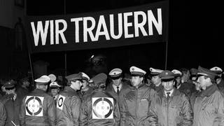 Mit einem schwarzen Transparent und der Aufschrift "Wir trauern" demonstrieren Polizisten während eines Trauermarsches durch die Frankfurter Innenstadt am 4. November 1987. Sie zeigen ihre Bestürzung über den Tod der am 2. November während einer Demonstration an der Startbahn West des Frankfurter Flughafens erschossenen zwei Kollegen.