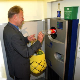 Bundesumweltminister Juergen Trittin steckt 2003 eine Flasche in einen Getränkeautomaten