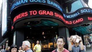 Touristen machen am 15. September 2008 Fotos auf dem New Yorker Times Square, während die Finanznachrichten des Tages im ABC-Newsticker angezeigt werden: Lehman goes bankrupt
