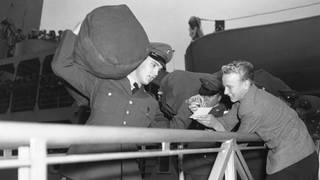 Der Rock-and-Roll-Sänger Elvis Presley gibt einem Fan ein Autogramm, während er nach seiner Ankunft in Bremerhaven am 1. Oktober 1958 sein Gepäck auf der Schulter über die Gangway schleppt