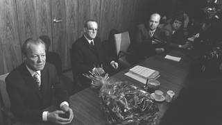 Willy Brandt (SPD, links) sitzt am 7. Mai 1974 am Tisch im Fraktionssaal, neben ihm Herbert Wehner. Auf dem Tisch ein Blumenstrauß. Am Vorabend hatte er beim Bundespräsidenten Gustav Heinemann seinen Rücktritt als Bundeskanzler eingereicht.