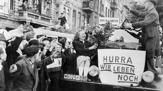 Unter dem Jubel von Bürger*innn verlassen am frühen Morgen des 12. Mai 1949 die ersten Busse Berlin in Richtung Westdeutschland