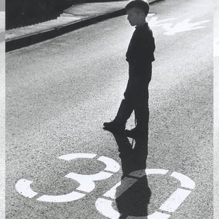 Ein Kind steht im Gegenlicht auf einer mit "30" gekennzeichneten Straße: 1983 fast eine Revolution – die Stadt Buxtehude führt in einem großflächigen Kernbereich Tempo 30 ein (Symbolbild)