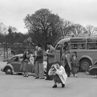 Reisebus und fotografierende Touristen vor dem Eiffelturm in Paris im 9. April 1955