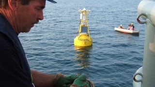 Ein Techniker arbeitet 2005 an Bord des deutschen Forschugsschiffs "Sonne", im Hintergrund zu sehen eine Boje, die Teil eines von GITEWS entwickelten Tsunami-Warnsystems sein wird. Das von deutschen und indonesischen Forschern entwickelte System umfasst Sensoren am Meeresboden und Bojen auf der Meeresoberfläche, die Erdbeben- und Tsunami-Aktivitäten messen sollen.