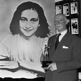 Otto Frank hält am 14. Juni 1971 in London den Golden Pan Award, der für den Verkauf von einer Million Exemplaren des berühmten Buchs seiner Tochter, "Das Tagebuch der Anne Frank" verliehen wurde, in der Hand. Im Hintergrund eine große Porträtaufnahme von Anne Frank.