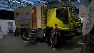 SWR-Reporterin Michelle Habermehl steht vor einem sehr großen Expeditionsmobil