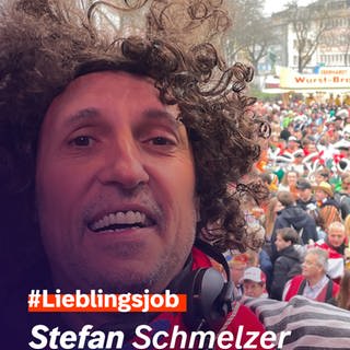 Regionalreporter Stefan Schmelzer mit Lockenperücke. Im Hintergrund Teilnehmer der Mainzer Fastnacht.