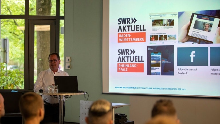 Stephan Lochner, Leiter des SWR Audio-Nachrichtenzentrums, hält eine Präsentation, die Beamten der Bundespolizei hören gespannt zu.