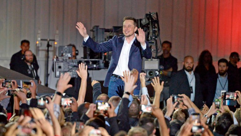 Elon Musk wird auf einer Bühne von seinen Fans gefeiert.
