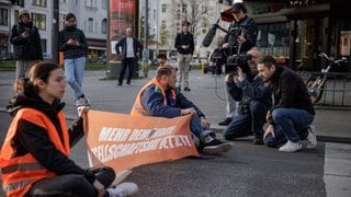 ARD Story: Radikal fürs Klima - Helden oder Kriminelle? Aktivisten der "Letzten Generation" werden bei einer Straßenblockade auf dem Kurfürstendamm in Berlin interviewt.