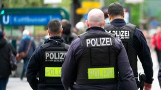 Drei uniformierte Polizeibeamte im Einsatz. Von hinten fotografiert.