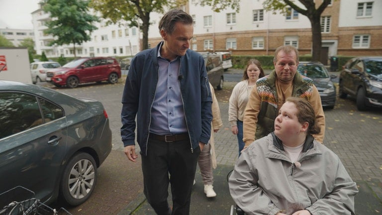 Sascha Becker mit Theo (im Rollstuhl) und seiner Familie auf dem Weg zu seiner Ärztin.