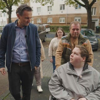 Sascha Becker mit Theo (im Rollstuhl) und seiner Familie auf dem Weg zu seiner Ärztin.