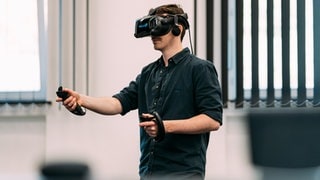 Sebastian Demuth beim Testen eines digitalen Produktes des SWR X Lab, er ist mit einem VR-Headset und zwei Controllern ausgestattet.