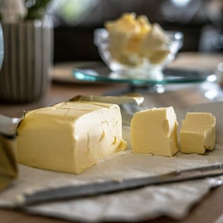 Ein Stück Butter liegt auf einem Frühstückstisch. Die Preise für Butter steigen. An Weihnachten könnte das Milcherzeugnis so teuer sein wie nie zuvor. Lohnt es sich, Butter einzufrieren oder selbst herzustellen?