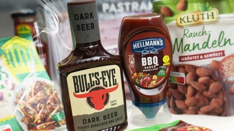 Barbecue-Saucen, Rauchmandeln und andere Produkte mit Raucharoma stehen auf einem Tisch. Raucharoma ist in der EU bald verboten. Wie ungesund ist geräuchertes?