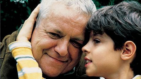 Albert flüstert mit seinem Opa Hermann und umarmt ihn dabei