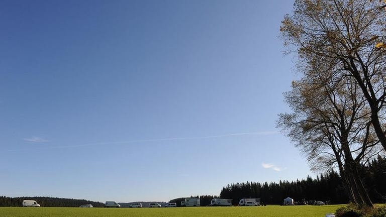 Viele SWR-Autos am Waldrand vor blauem Himmel und grüner Wiese