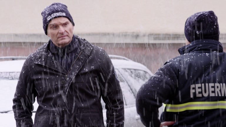 Uli Zimmermann in Uniform im Schneegestöber. Von hinten sieht man Jürgen.