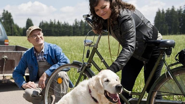 Eva streichelt Hofhund Willy, Karl sitzt in den Knien daneben