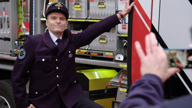 Uli Zimmermann lässt sich in Uniform an einem Einsatzfahrzeug fotografieren