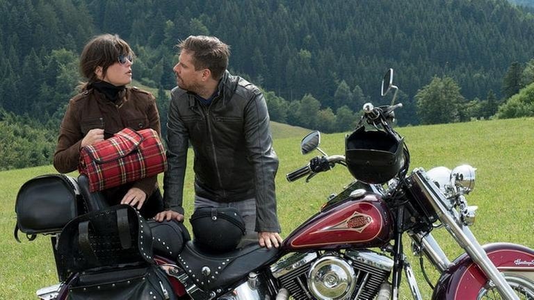 Eva und Andreas mit dem Motorrad vor einer großen Wiese