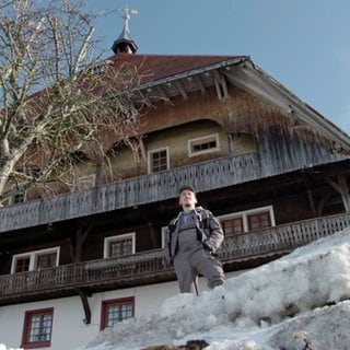 Sebastian steht vor dem Fallerhof im Schnee und sieht in die Ferne