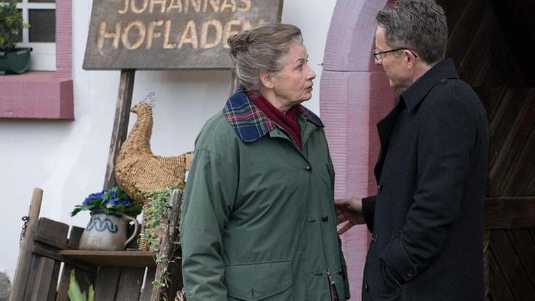 Johanna und Bernhard stehen vor dem Hofladen und unterhalten sich