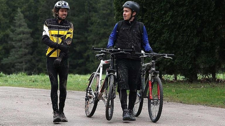 Sebastian schiebt zwei Fahrräder, Albert geht neben ihm her und  hält sich den verletzten Arm