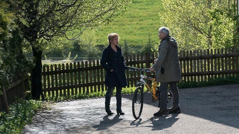 Bea und Karl stehen vor dem Fallerhof und unterhalten sich.