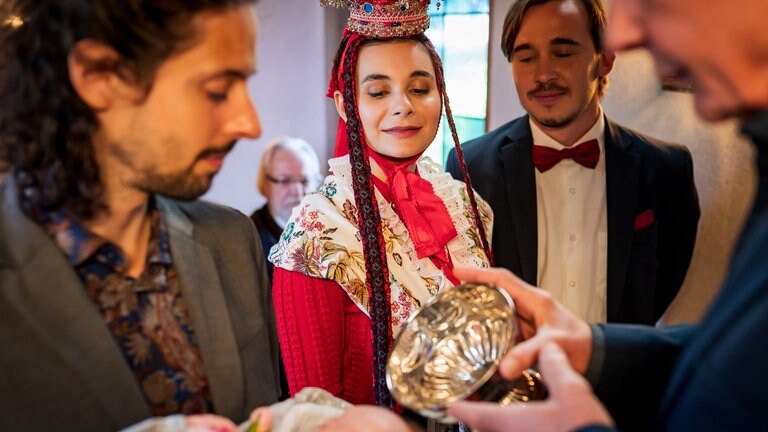 Albert (Alessio Hirschkorn) hält Matteo Wenzel Faller, der getauft wird. Jenny (Julia Obst) und Sebastian (Dominik Stricker) sehen zu.