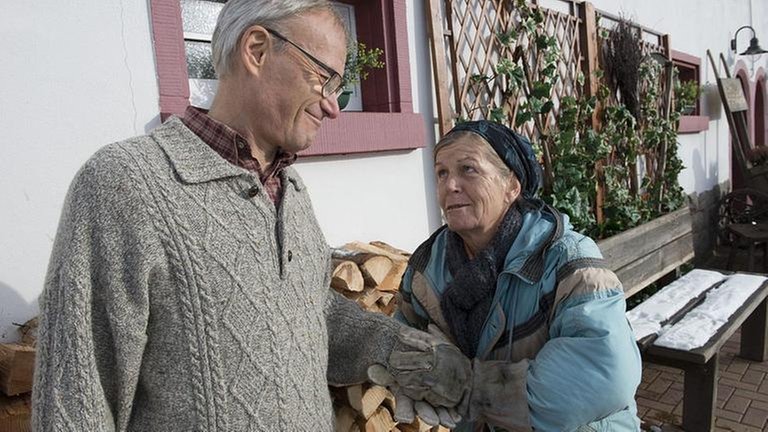 Karl und Lioba stehen vor einer Holzsteig und sprechen miteinander