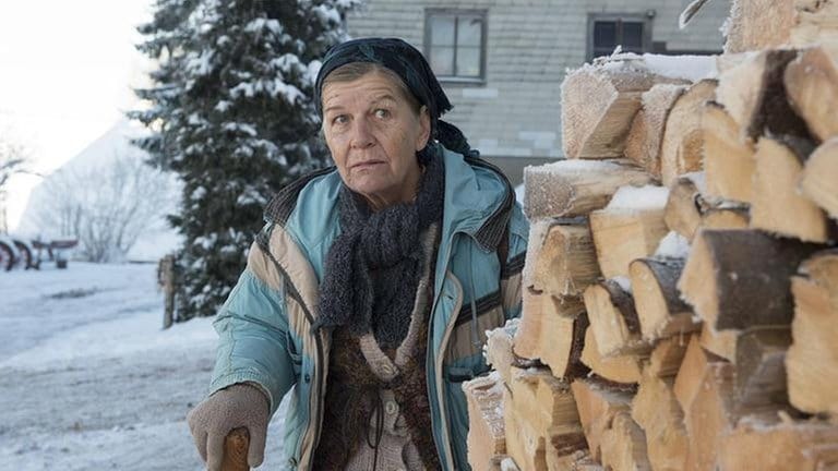 Lioba guckt hinter einem Holzstapel hervor