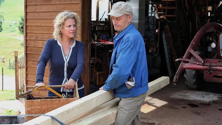 Bea und Karl beladen einen Anhänger mit Holz