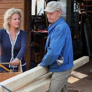 Bea und Karl beladen einen Anhänger mit Holz