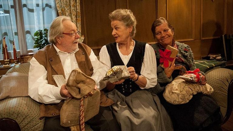 Johanna, Hermann und Lioba sitzen nebeneinander und haben ihre Weihnachtsgeschenke in den Händen