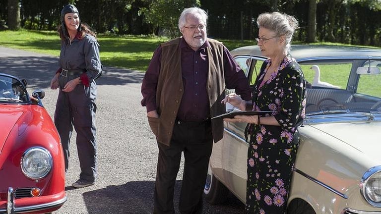 Sabine, Hermann und Johanna stehen vor den Oldtimern, mit denen sie die Rallye fahren wollen