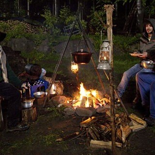 Toni, Albert und Sebastian sitzen im Wald an einem Lagerfeuer