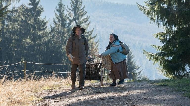 Sebastian zieht einen Holzwagen hinter sich her, Lioba läuft neben ihm