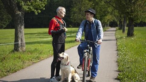 Karl im Laufdress und Sebastian auf seinem Fahrrad in der Allee zum Fallerhof