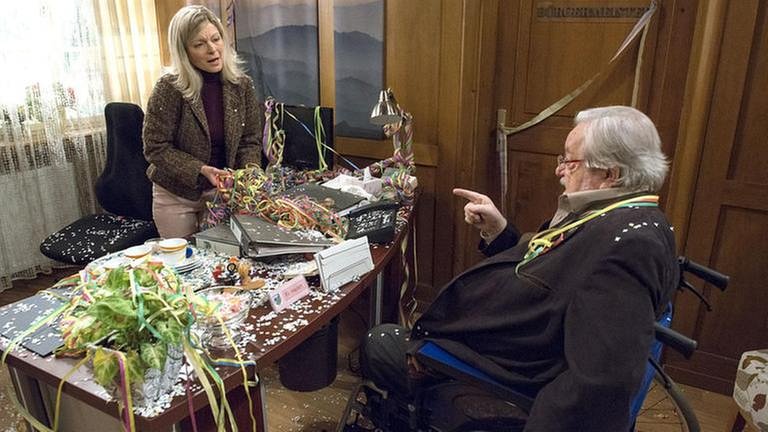 Frau Heilert und Hermann in Frau Heilerts Büro, Hermann sitzt im Rollstuhl, im Büro