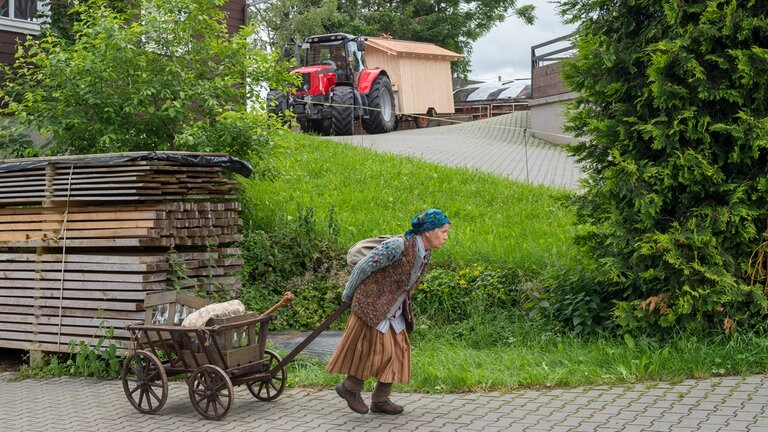 Lioba zieht ihr Wägelchen, im Hintergrund zieht Constantins Schlepper Johannas Hühnerstall