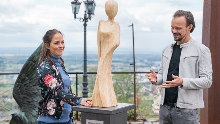 Sophie und Constantin vor einer von Sophie gschnitzten Holzskulptur