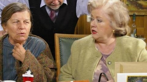 Lioba und Leni sitzen an Hermanns Schreibtisch im Rathaus, Hermann steht dahinter