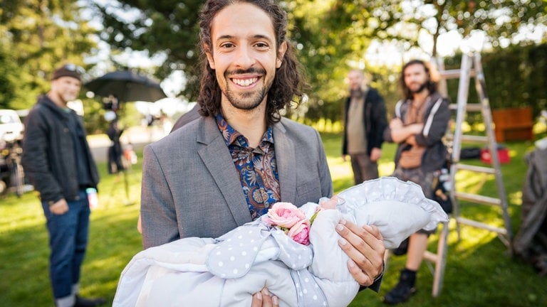 Alberet (Alessio Hirschkorn) hält den Täufling beim Dreh auf dem Fallerhof