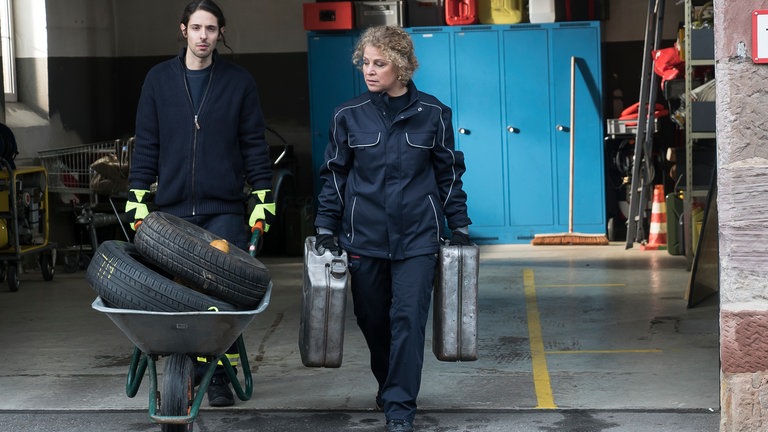 Albert und Bea schleppen Kanister aus der Feuerwehrwagenhalle