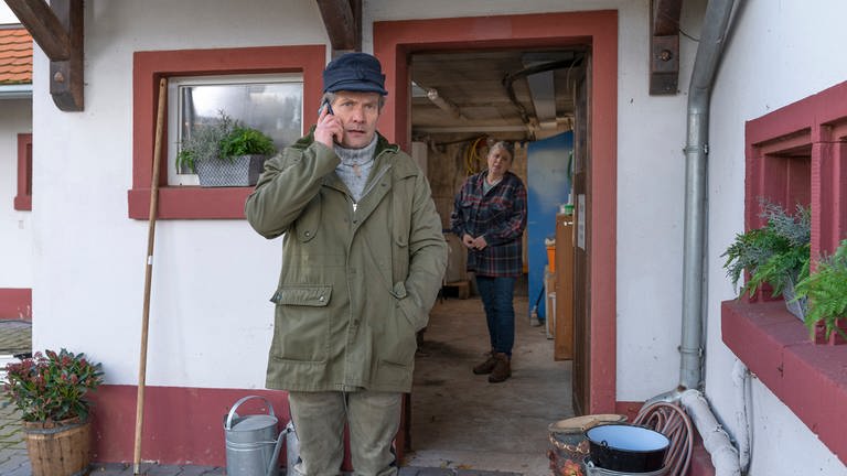 Markus Riedle telefoniert, im Hintergrund steht Evelyn